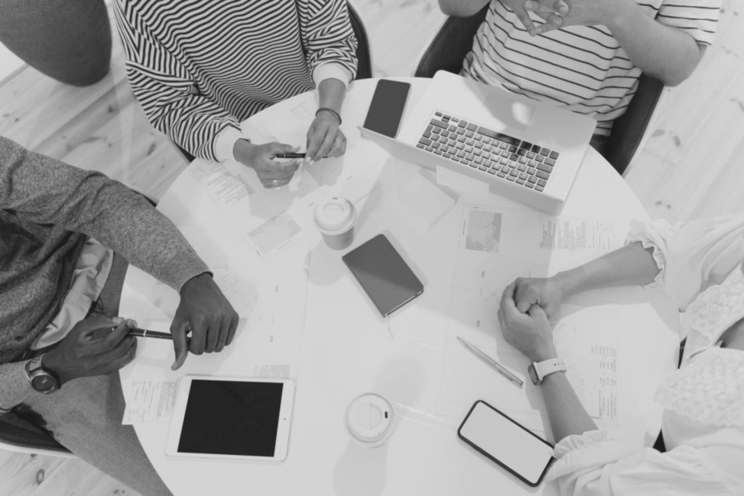Finance professionals engaged in collaborative discussion around conference table with charts and reports